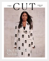 Portrait of Nia Long wearing a patterned white coat against a textured neutral wall for The Cut magazine.