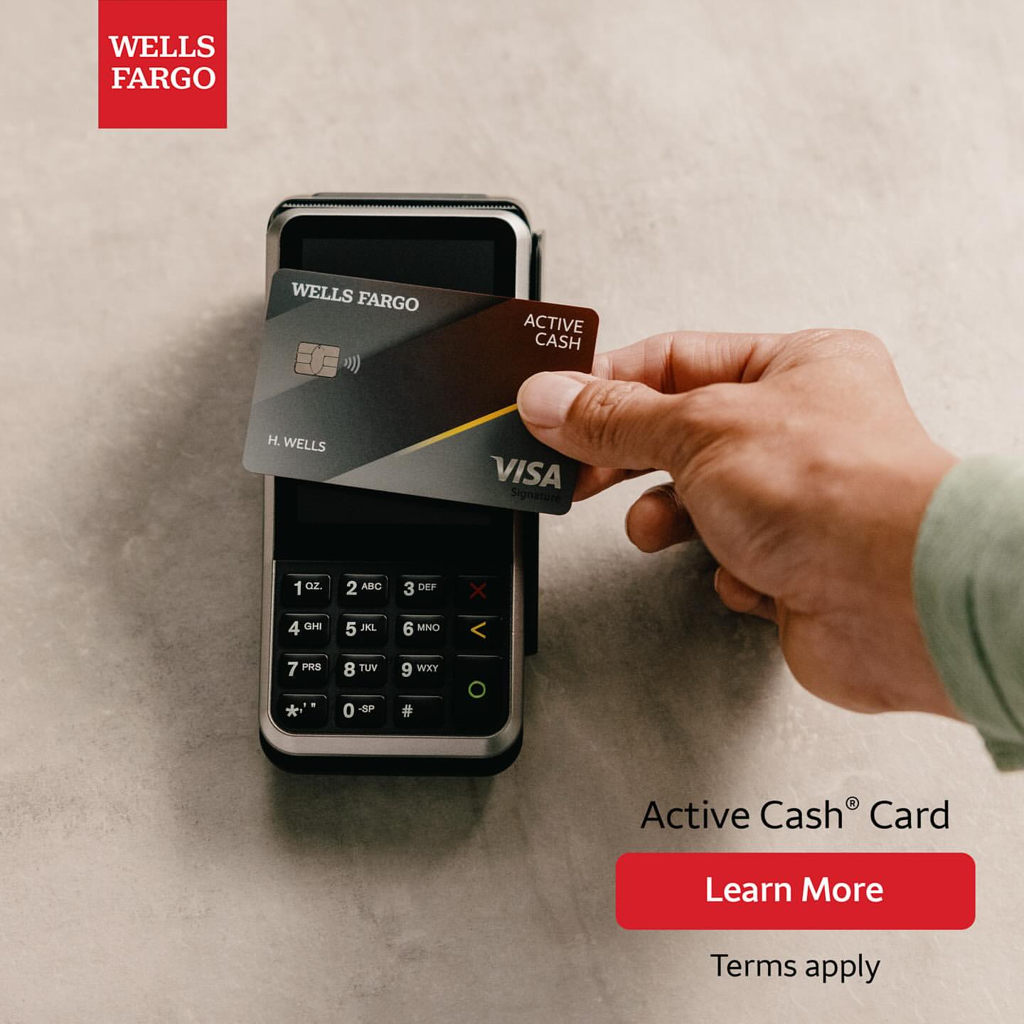 Hand holds Wells Fargo Active Cash Visa card over payment terminal, red 'Learn More' button for details, Wells Fargo logo displayed.