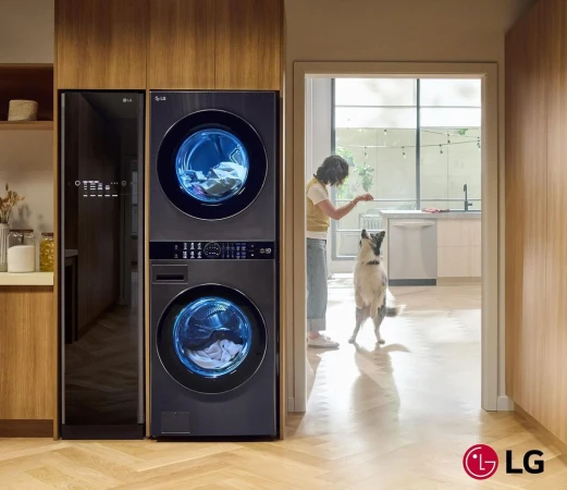 Modern laundry setup with LG washer and dryer, side storage, and a woman interacting with her dog in the background of a well-lit interior.