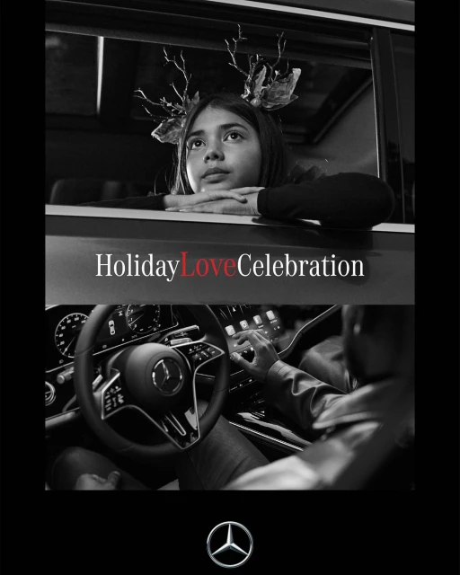 A child with holiday antlers looks up from a car window, with the steering wheel of a Mercedes-Benz in the foreground, in black and white.