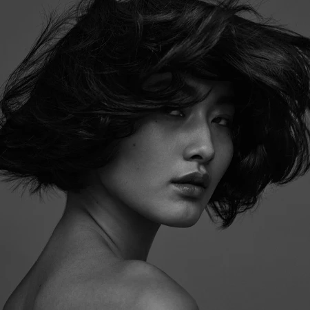 Close-up monochrome portrait of a woman with short dark hair in motion, captured by photographer Ralph Mecke.