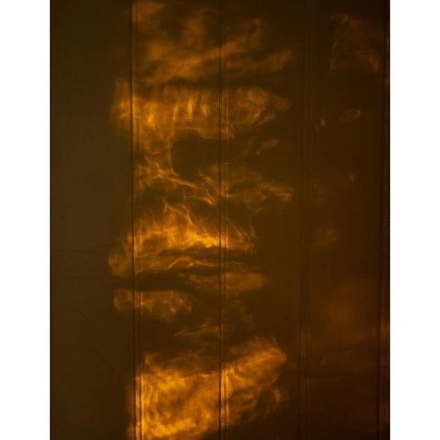 Abstract amber light patterns on vertical wood panels create a warm, textured, and visually intriguing background.