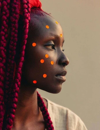 Profile portrait of a Black woman with long thick red braids and orange dot stickers on her face by Ramon Haindl