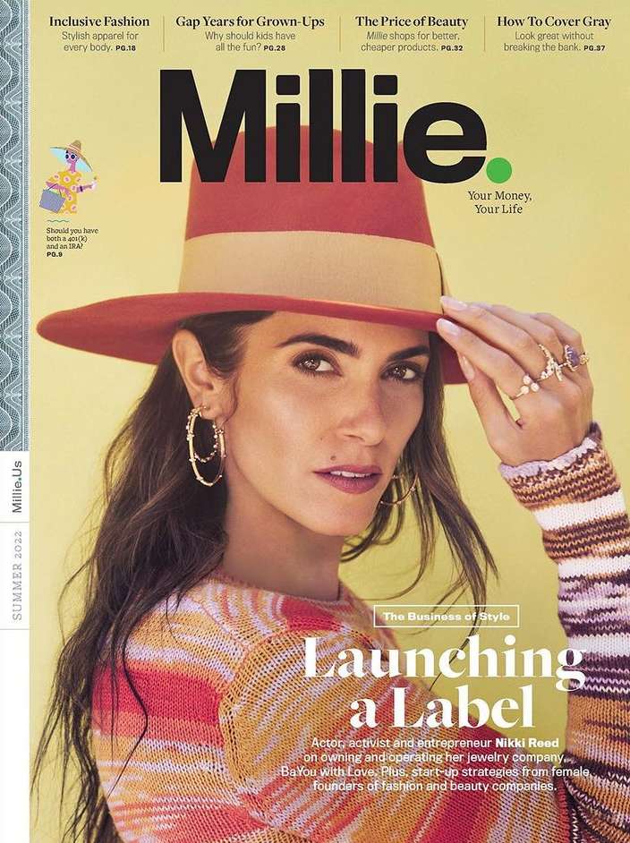 Close-up magazine cover portrait of Nikki Reed wearing a red fedora and striped knit sweater against a yellow background.