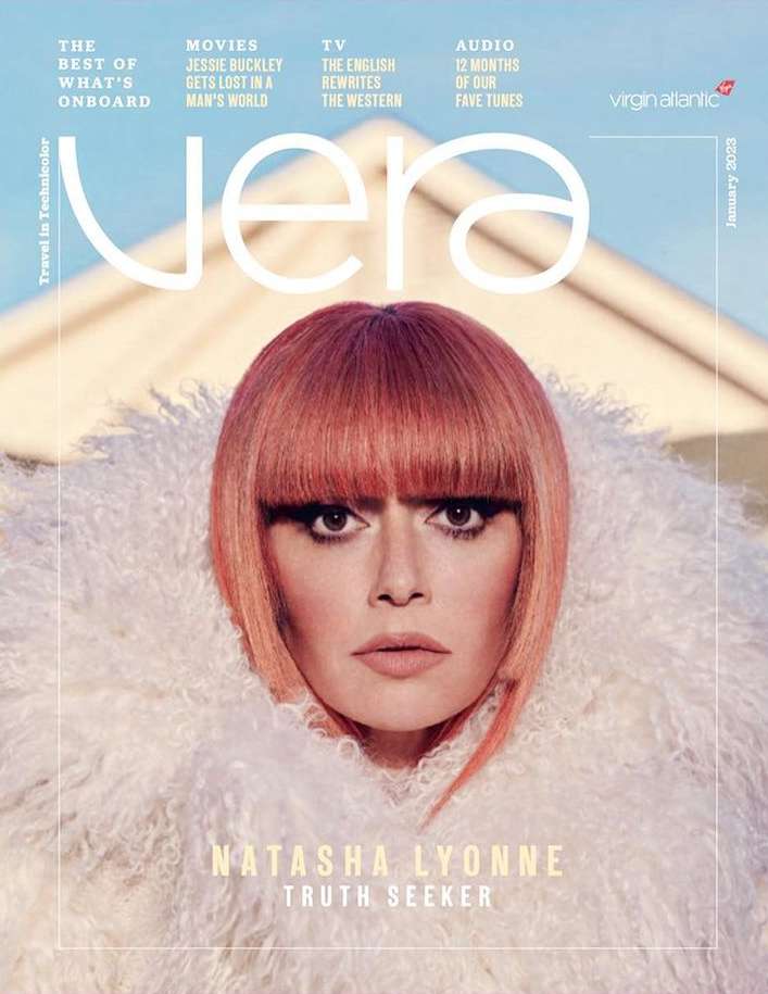 Magazine cover featuring Natasha Lyonne with an orange bob haircut, wearing a white faux fur coat, with architectural elements in the background.