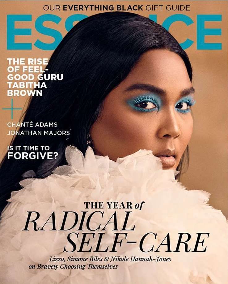Essence magazine cover featuring Lizzo with blue eyeshadow and a white ruffled collar, posing against a tan background.