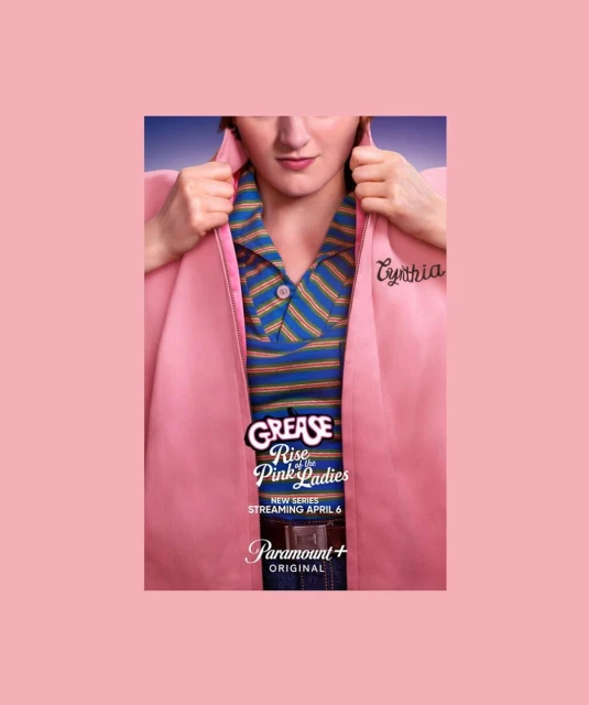 Promotional image for 'Grease: Rise of the Pink Ladies' featuring actor in Pink Ladies jacket, striped shirt, and belt buckle.