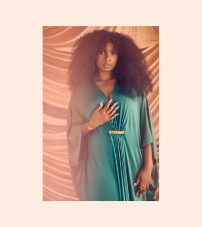 Portrait of Jennifer Hudson in a flowing green caftan standing against a draped satin backdrop by Ramona Rosales