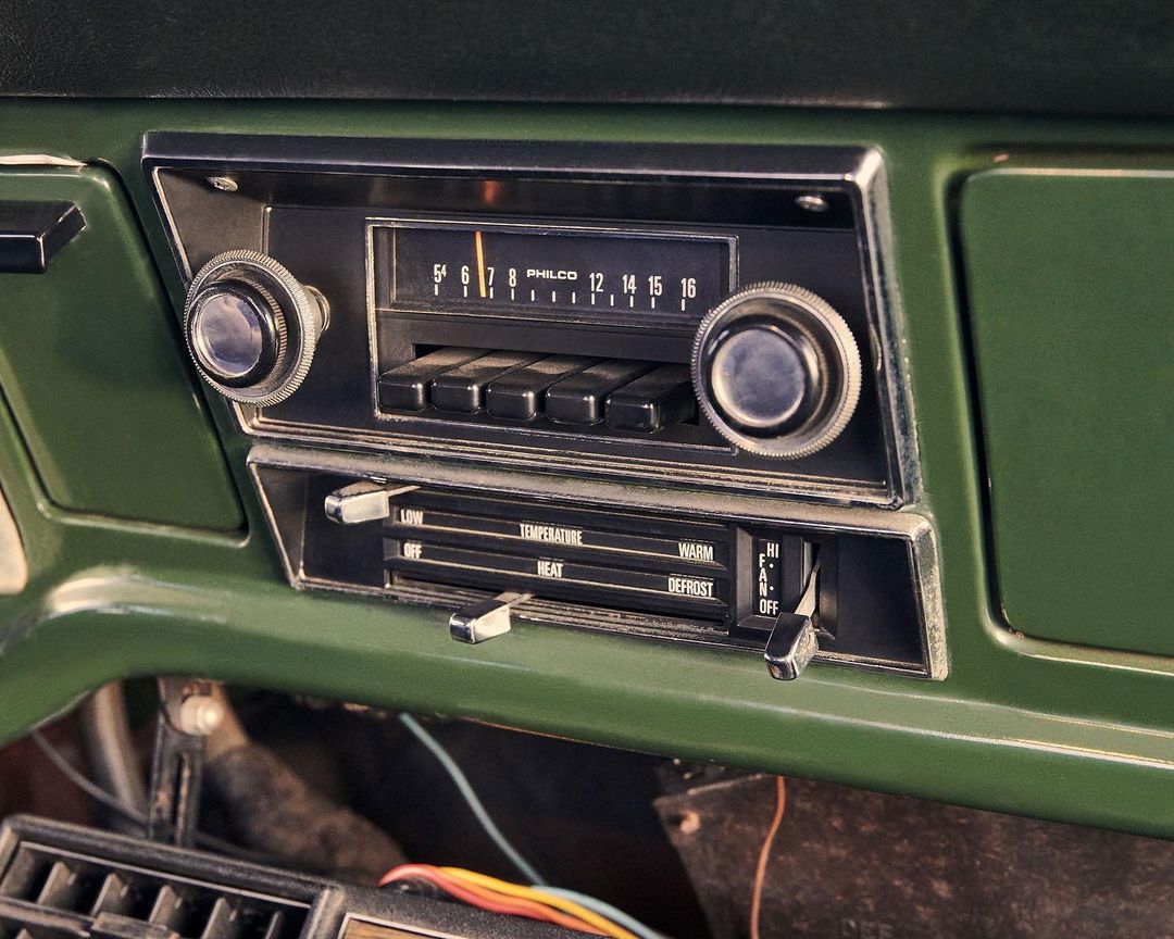 Vintage car dashboard featuring a Philco radio with knobs and buttons, along with temperature and heat control levers, showcasing classic automotive design.