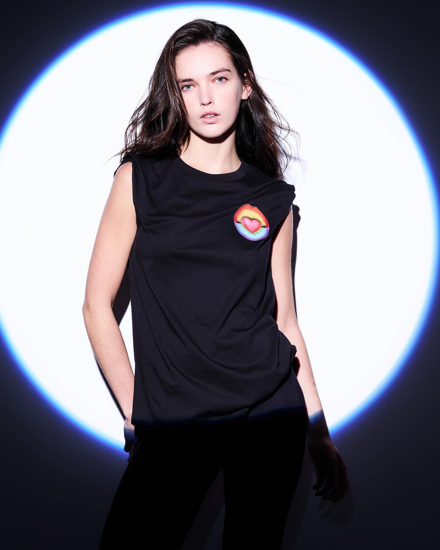 Woman in black sleeveless t-shirt standing in front of a circular blue projection light