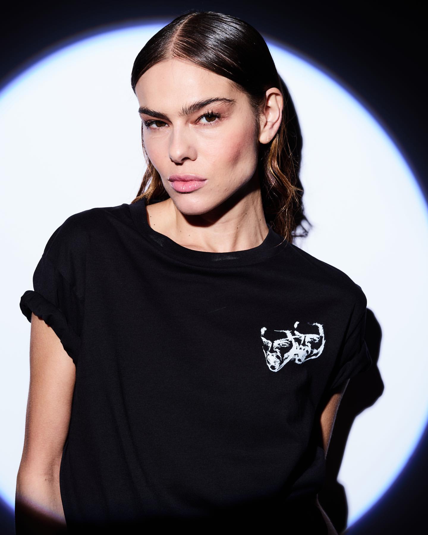 Portrait of a woman wearing a black t-shirt under a spotlight, photographed by Rankin in New York.