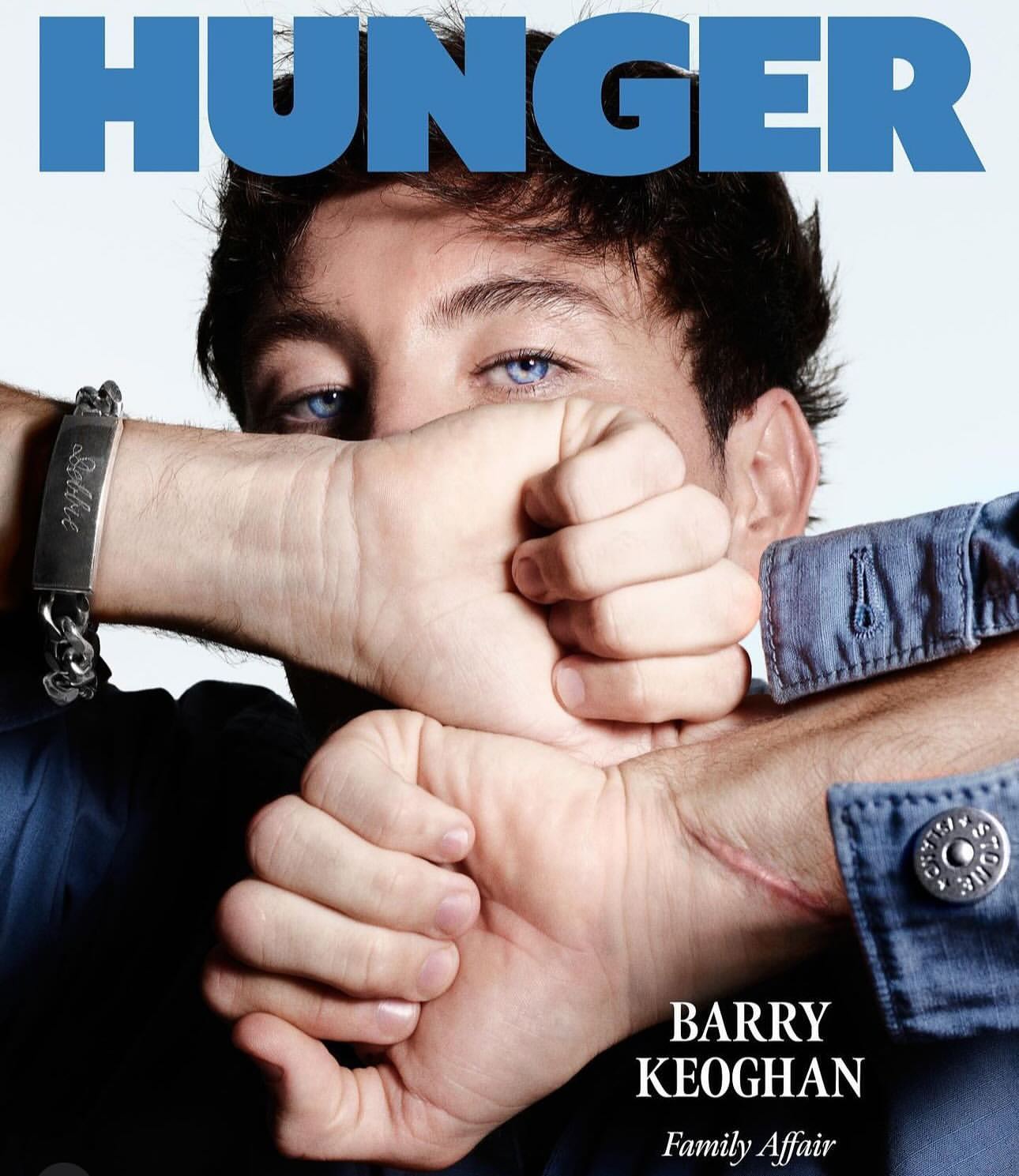 Close-up magazine cover featuring Barry Keoghan with blue eyes, hands covering mouth, wearing a blue denim shirt and metal bracelet.