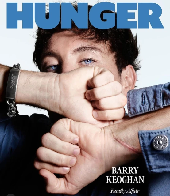 Close-up magazine cover featuring Barry Keoghan with blue eyes, hands covering mouth, wearing a blue denim shirt and metal bracelet.