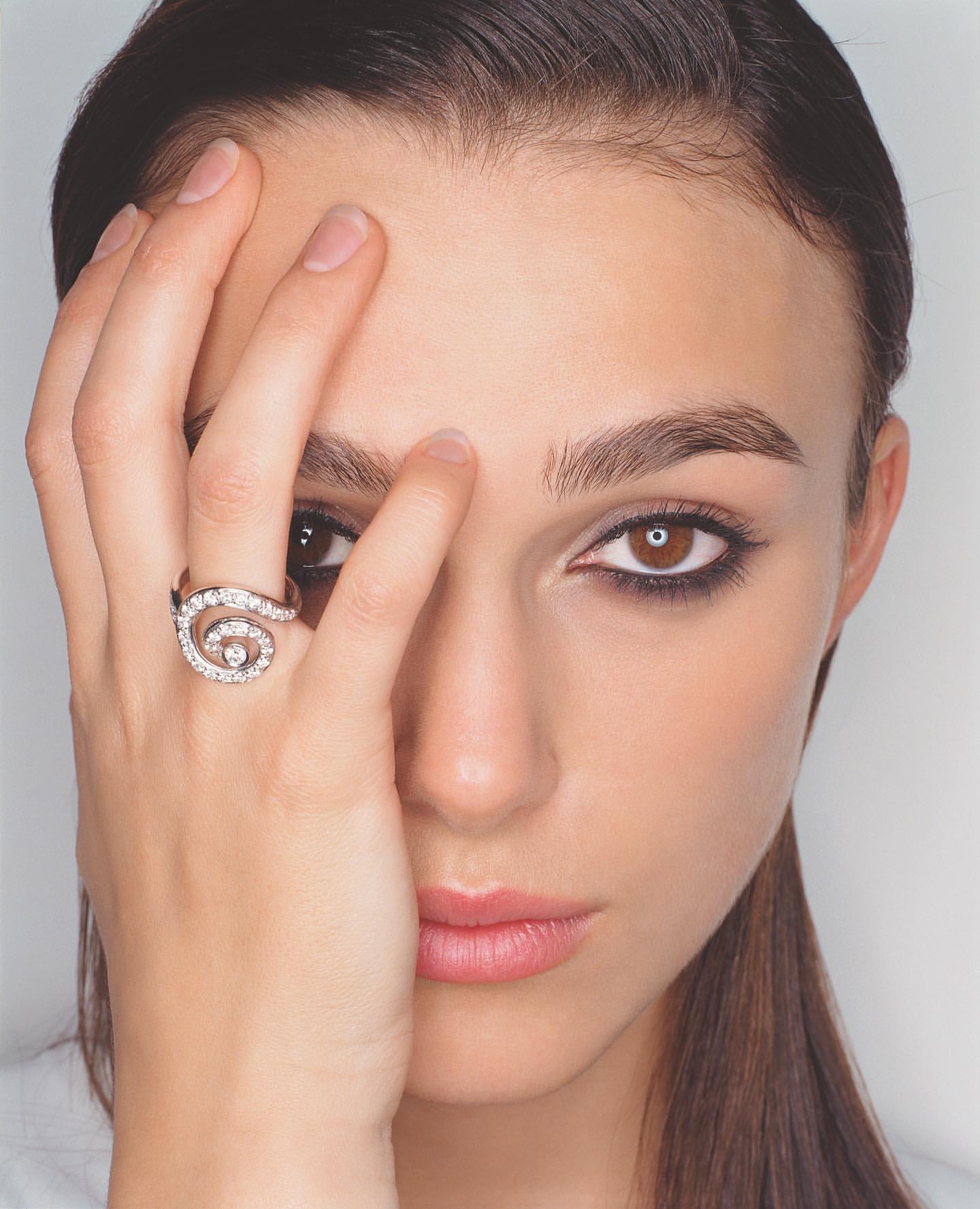Close-up portrait of a woman holding her hand to her face, showcasing a diamond spiral ring against a plain white background.