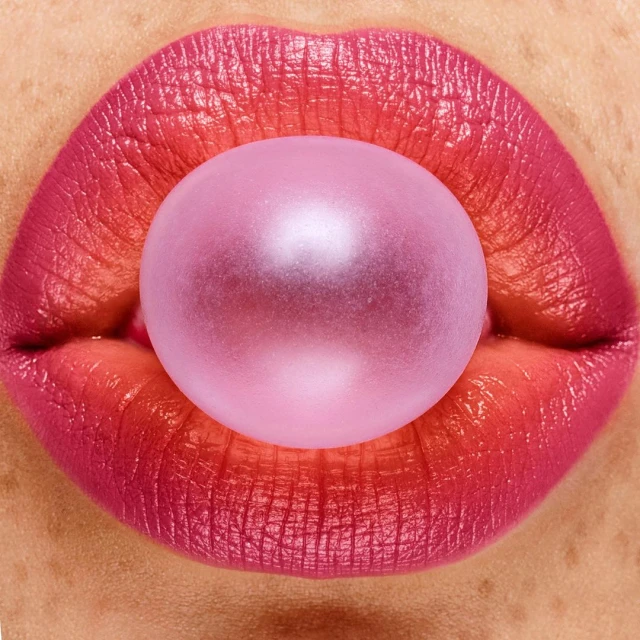 Macro shot of pink lips with a bubblegum bubble, creating a vibrant and playful close-up image focused on beauty and texture.