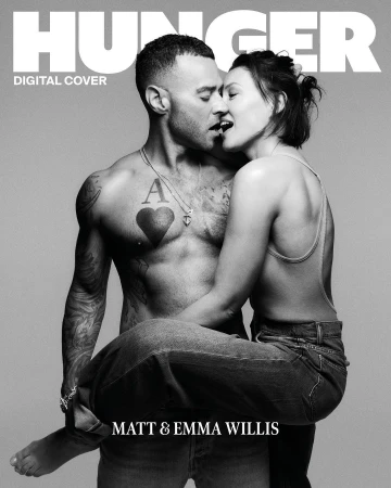 Black and white magazine cover featuring a shirtless man with tattoos holding a woman in his arms, both with mouths open.