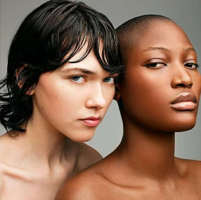 Close-up studio portrait of two diverse female models with shaved head and short hairstyle, showcasing skincare and beauty.