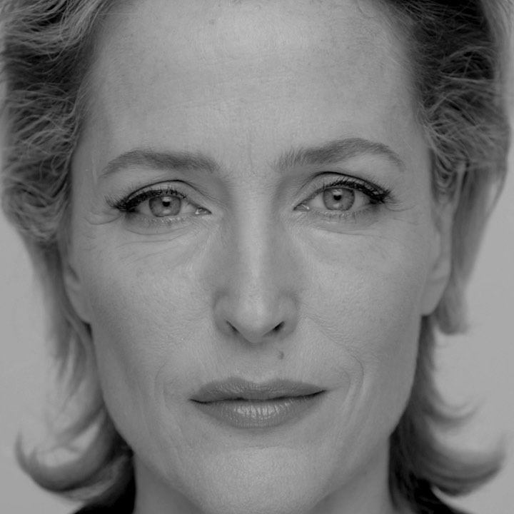 Close-up portrait of an adult woman with light skin and hair, looking directly at the camera with a neutral expression, in black and white.
