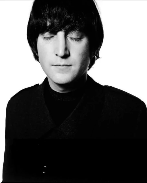 Monochrome portrait of adult male with dark hair and eyes closed, wearing a dark jacket against a bright white background. 