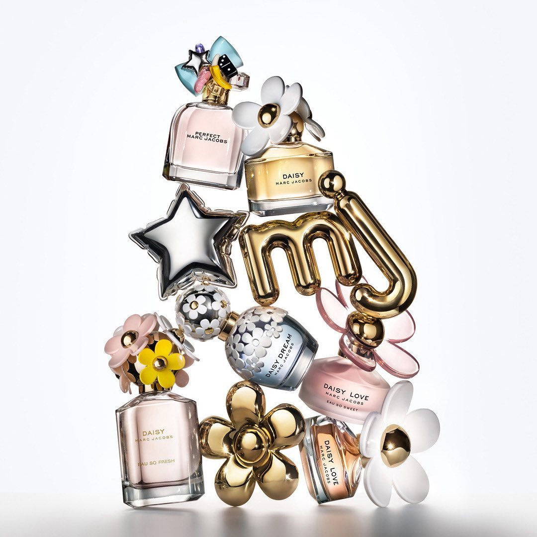 Elevated view of various Marc Jacobs perfume bottles stacked on top of each other, with different styles of flowers and logos.