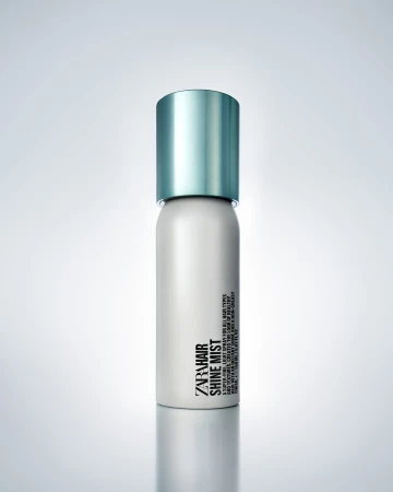 A single can of Zara Hair Shine Mist sits on a white surface with soft studio lighting and a subtle gradient background.