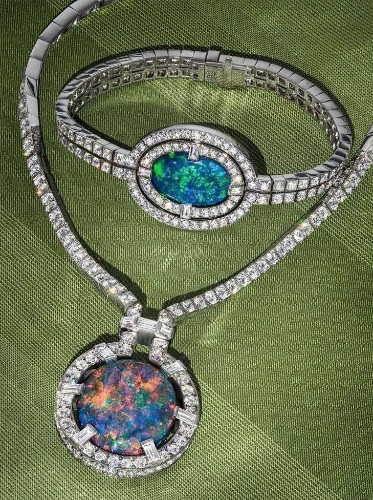 Elegant white gold jewelry set featuring a necklace and bracelet, each adorned with opal cabochons and diamond accents, on green fabric.