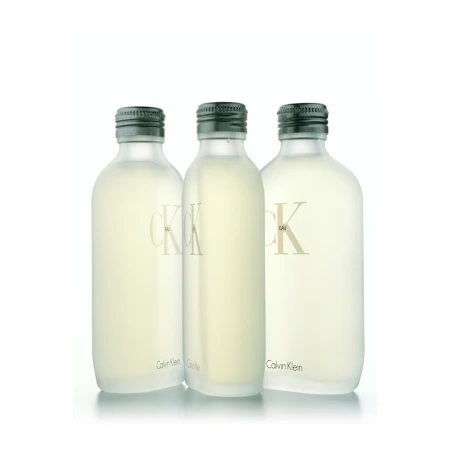 Three clear Calvin Klein CK One Eau de Toilette bottles stand in a row against a white background, displaying a minimalist aesthetic.