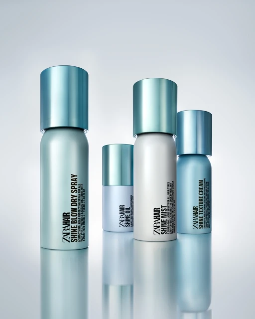 Four Zara Hair styling products including Shine Blow Dry Spray, Shine Oil, Shine Mist and Shine Texture Cream with light blue accents.