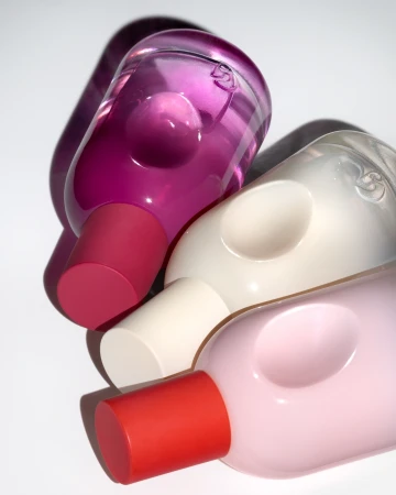 Three colorful plastic bottles with rounded shapes and cylindrical tops are neatly arranged on a bright white surface.