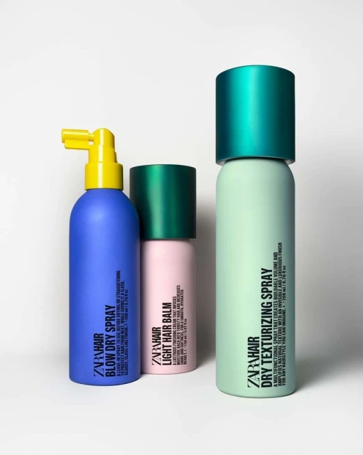 Three ZARA hair styling products: Blow Dry Spray (blue), Light Hair Balm (pink), and Dry Texturizing Spray (green), on a white background.