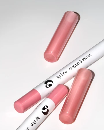 Close-up of two lip liner crayons with pink tips and two matching caps on a white surface, showcasing beauty product design.