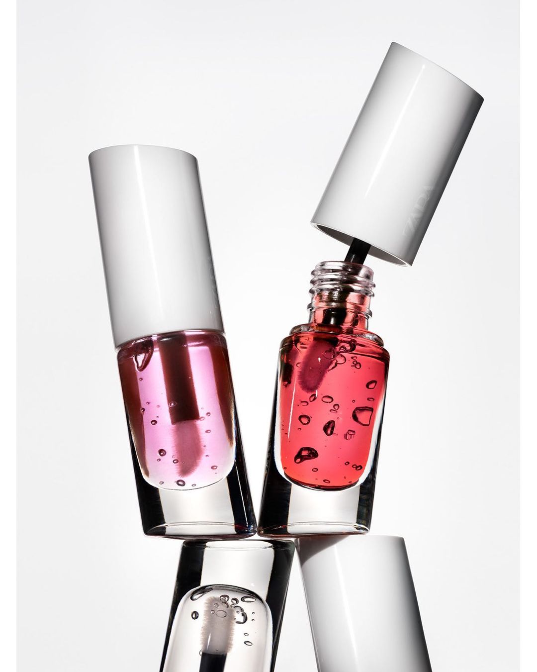 Close-up of stacked glass bottles containing colorful liquid and white caps, conveying a beauty and cosmetics product shot in studio.