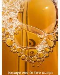 Macro shot of amber liquid with foamy soap bubbles clustered at the top and visible text at the bottom.