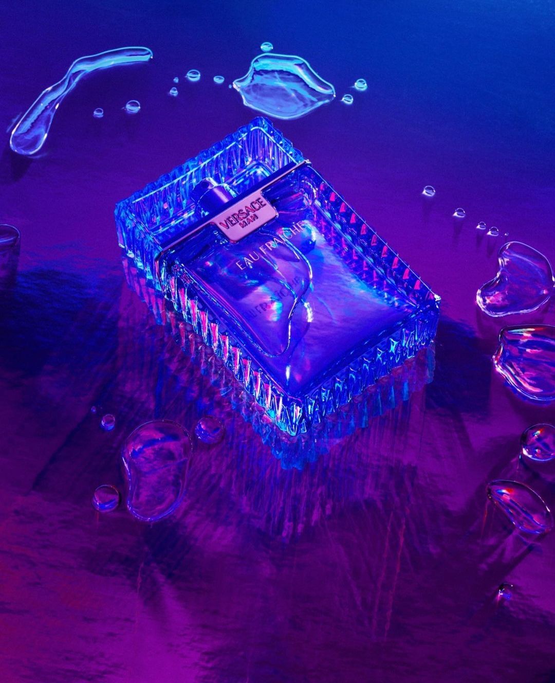 Crystal Versace Eros cologne bottle displayed on a purple reflective surface with water droplets, emphasizing luxury and fragrance.