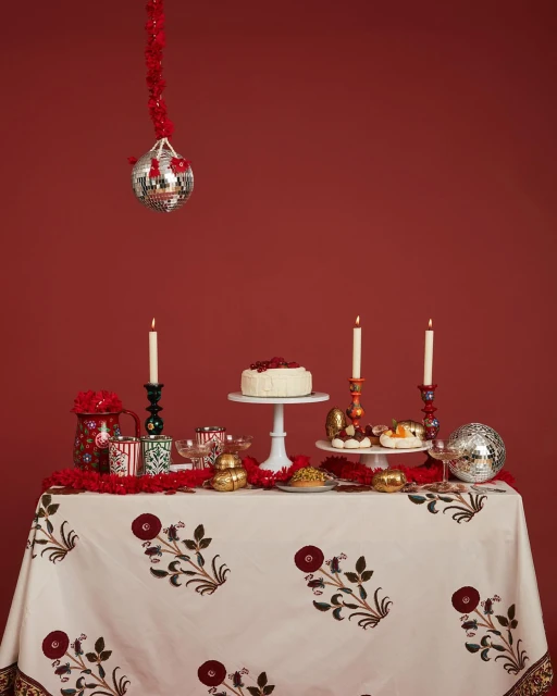 Festive dessert table featuring cake, pastries, candles, and disco balls against a red backdrop, creating a vibrant celebration scene.