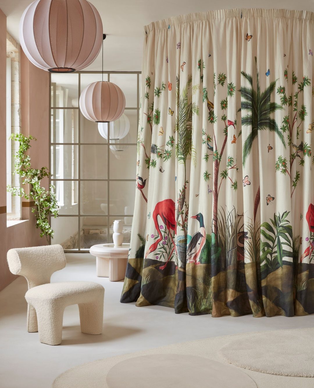 Interior design with patterned curtains featuring jungle animals, a cream-colored chair, modern lighting, and decorative room accents.