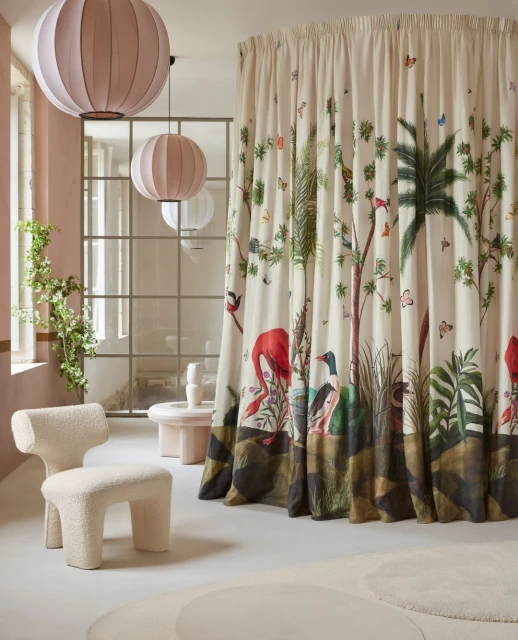 Interior design with patterned curtains featuring jungle animals, a cream-colored chair, modern lighting, and decorative room accents.