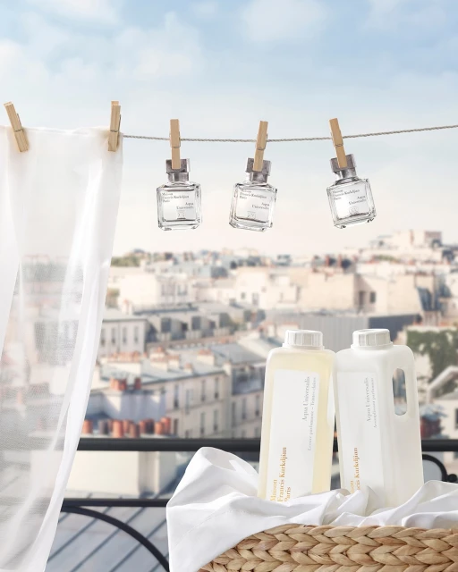Laundry detergent and perfume bottles arranged with clothespins, a woven basket, and a cityscape background create a clean and fresh aesthetic.