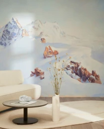 Modern interior with cream sofa, round coffee table, and a large wall mural depicting snowy mountain peaks.