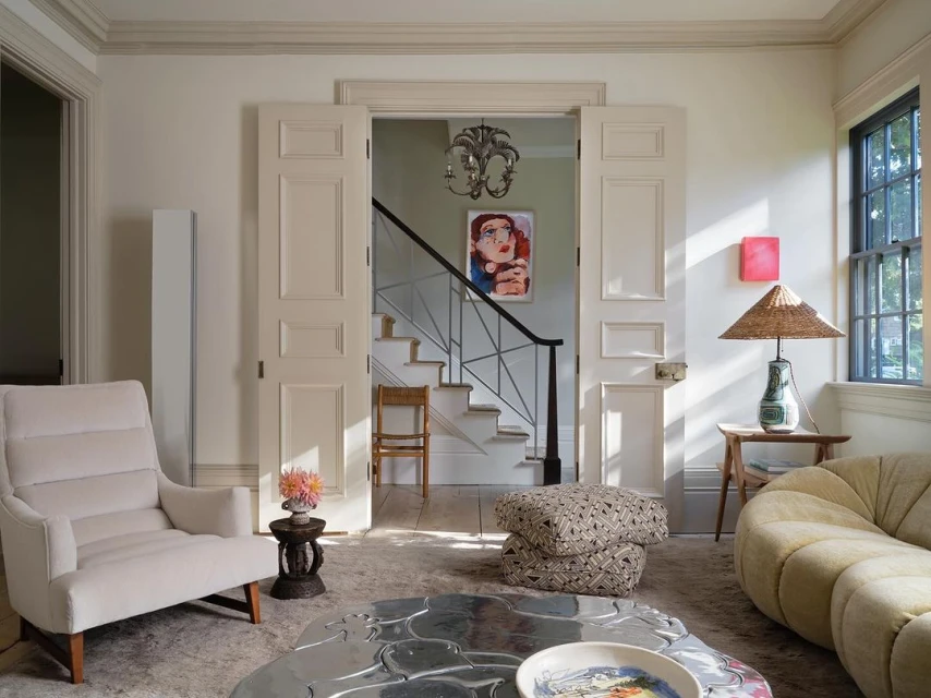 Interior view of a stylish living room with a cream sofa, chairs, patterned cushions, and a decorative table on a patterned rug.