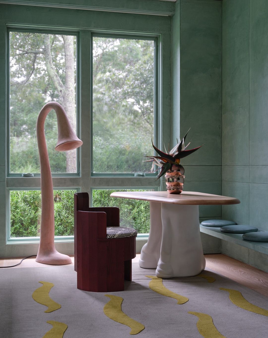 Artistic room interior features a bulbous floor lamp, angular chair, table with vase, and pale green color scheme with creative rug design.