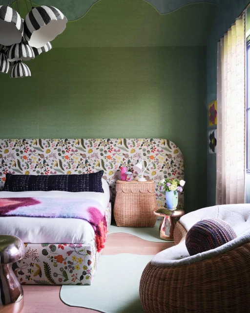 Interior design of a bedroom featuring a floral headboard, patterned bedding, wicker nightstand, and striped pendant lights.