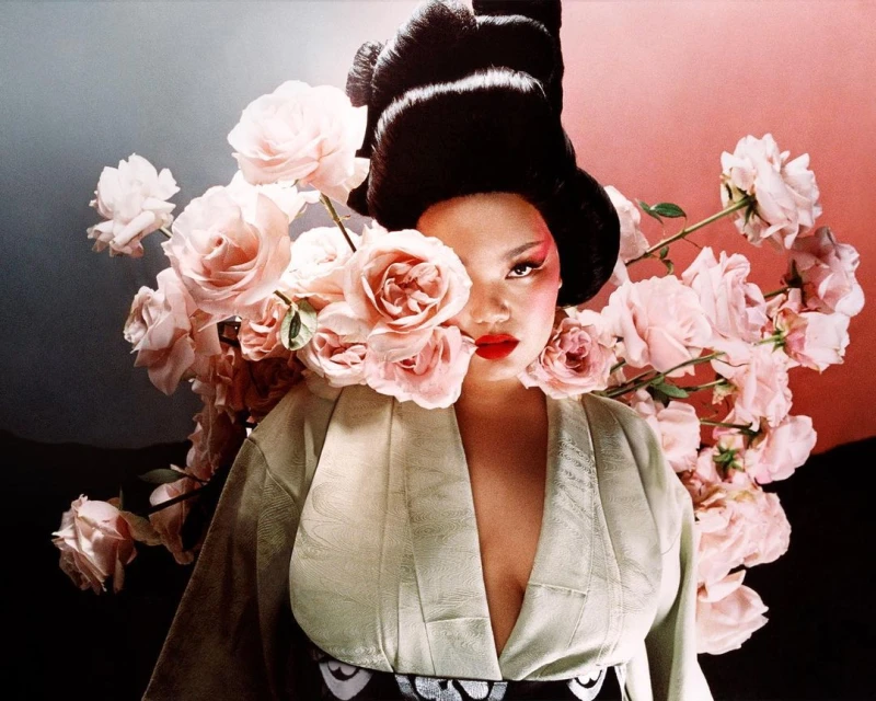 Artistic portrait of an Asian woman wearing a kimono with a dramatic hairstyle, pale skin, and surrounded by light pink roses.