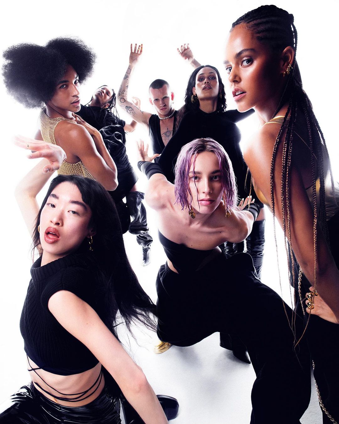 Group of diverse models in black attire posing dynamically against a bright white background, photographed by Rémi Lamandé