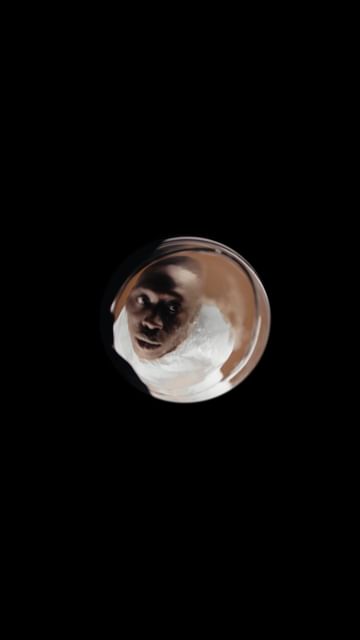 A digital rendering of a man's face within a transparent orb against a stark black background, showcasing a surreal and modern aesthetic.