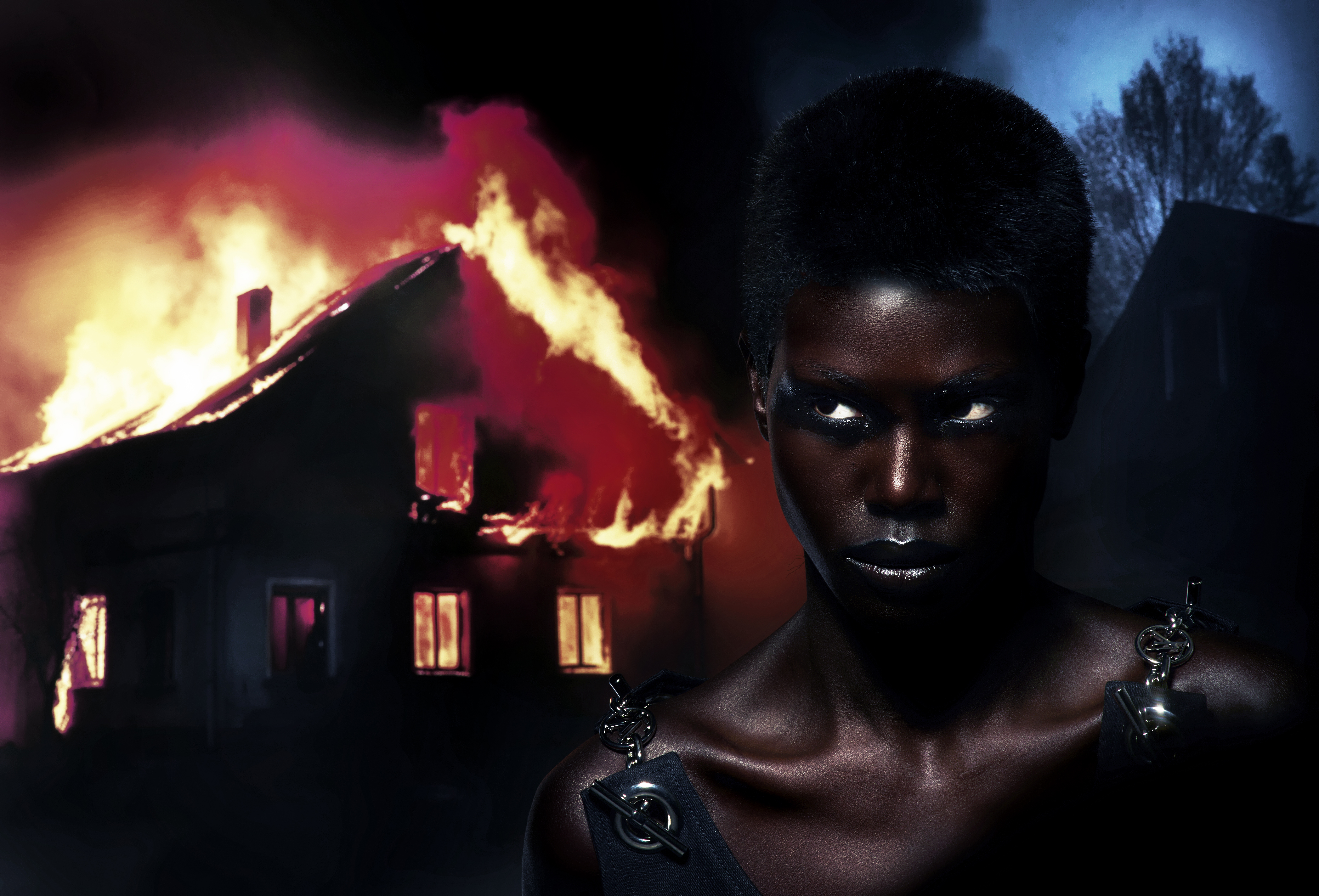 Striking portrait of a woman against a fiery house backdrop, creating a dramatic contrast with intense lighting and bold visual elements.