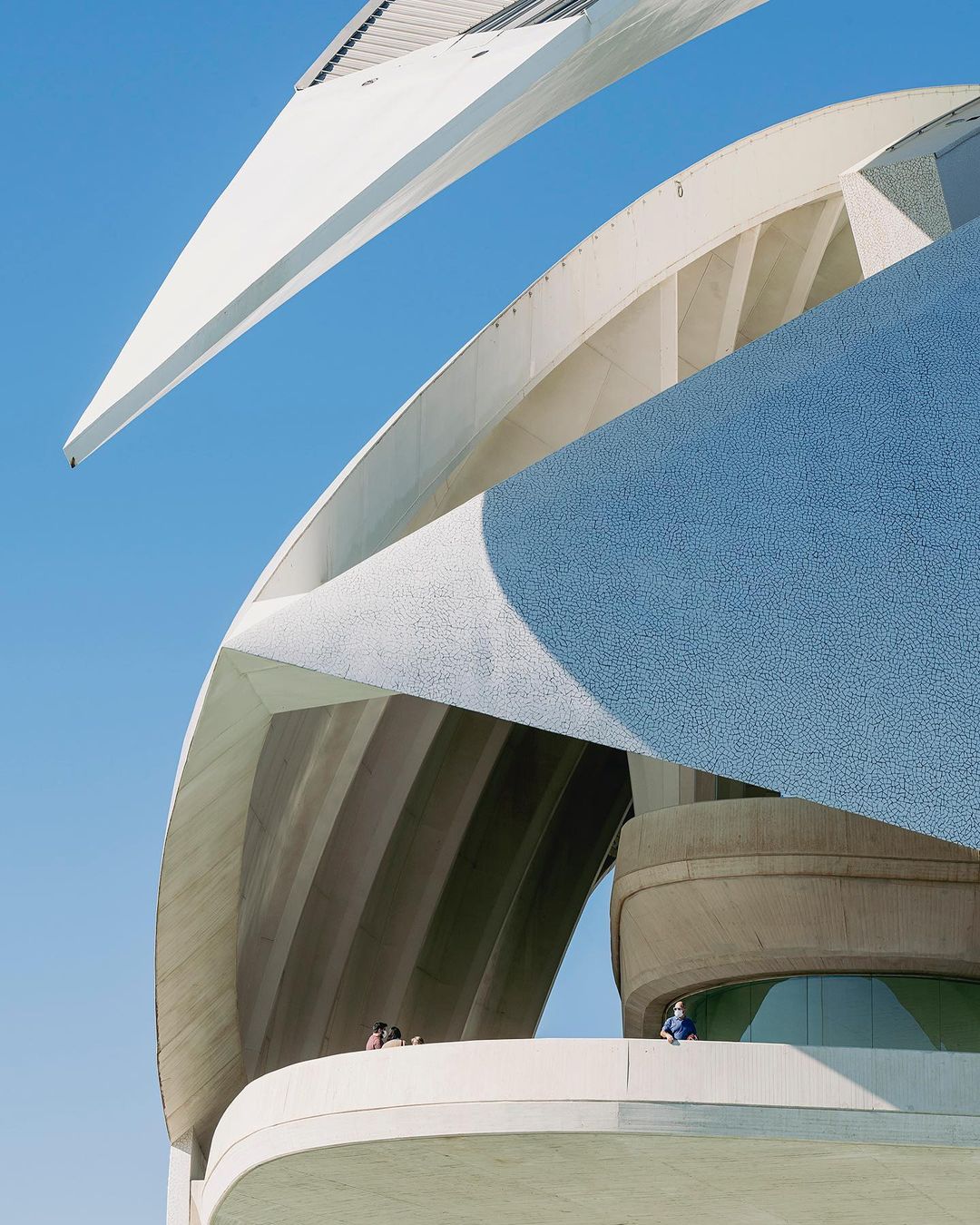 City of Arts and Sciences in Valencia, Spain, featuring modern architecture, patterned facades, and clear blue sky, viewed from a low angle.