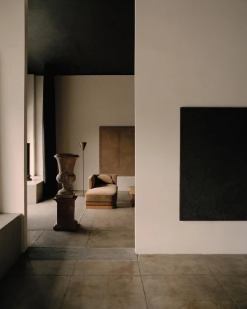 Living room with chaise lounge, floor lamp, and large dark painting on a light wall in a minimalist neutral interior design.
