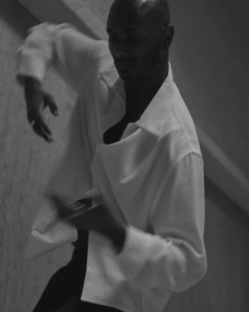 Monochrome portrait of a bald man in a white button-down shirt moving dynamically, captured in New York by Rich Stapleton.