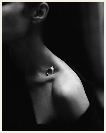 Close-up monochrome portrait of a woman wearing a silver ring resting in her collarbone by Rich Stapleton